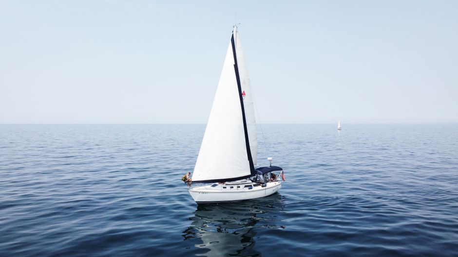 A peaceful sailboat gliding across calm Lake Michigan under a clear blue sky.