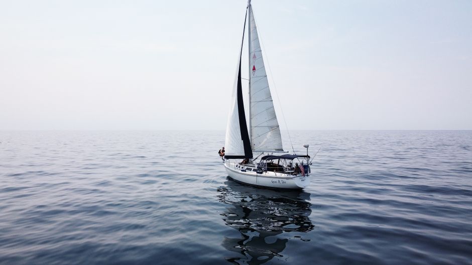 A solitary sailboat gracefully navigates the calm waters of Lake Michigan under a clear sky.