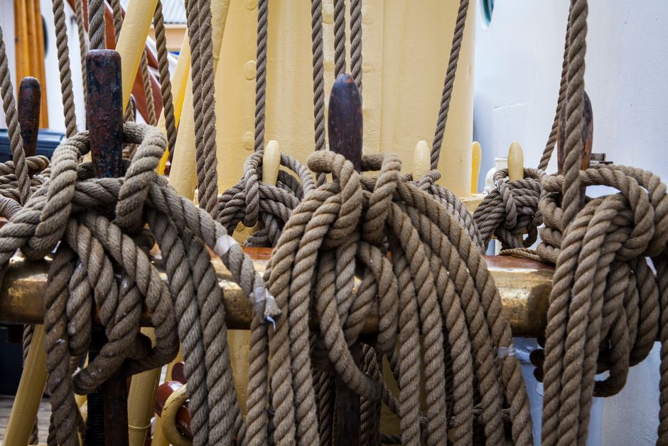 Close-up view of tightly knotted ropes on a sailing ship's deck, highlighting nautical craftsmanship.